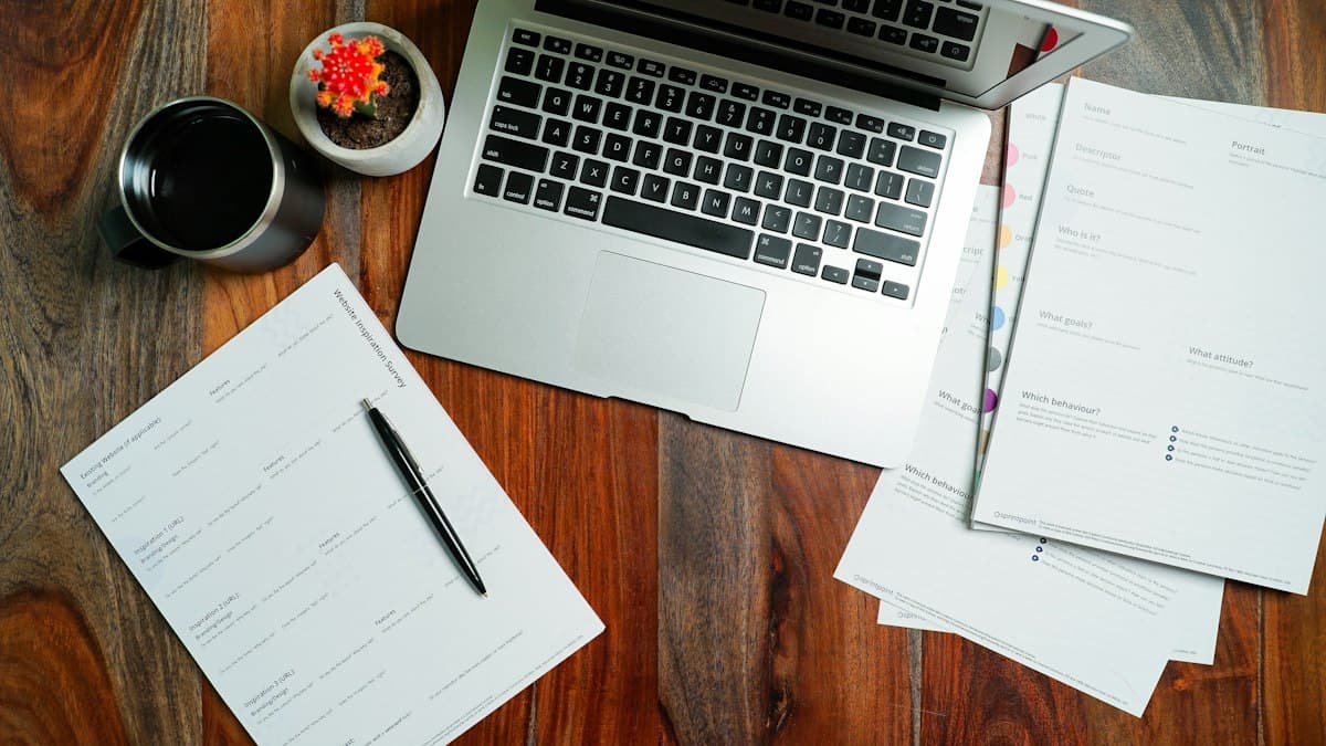 A laptop, notes and coffee on a wooden desk