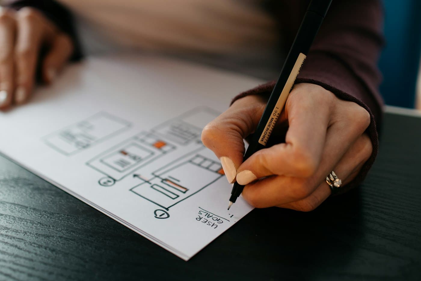 A hand sketching a website wireframe on paper