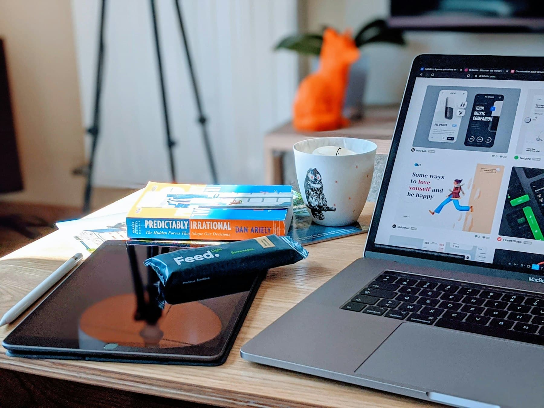 A laptop on a designer's desk beside sketches and a tablet